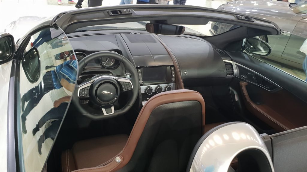 Pohľad do interiéru cez otvorenú strechu do hnedého koženého interiéru Jaguar F-Type Roadster 